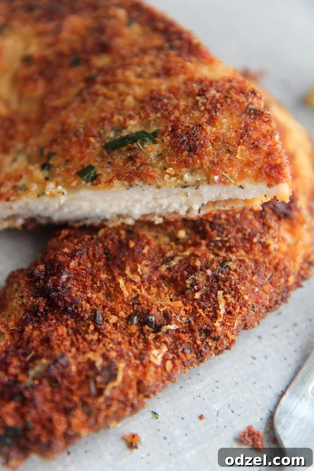 Golden Crunchy Chicken Cutlets 4 A fried chicken cutlet, perfectly golden and crispy, sliced in half to reveal its juicy interior and tender texture.