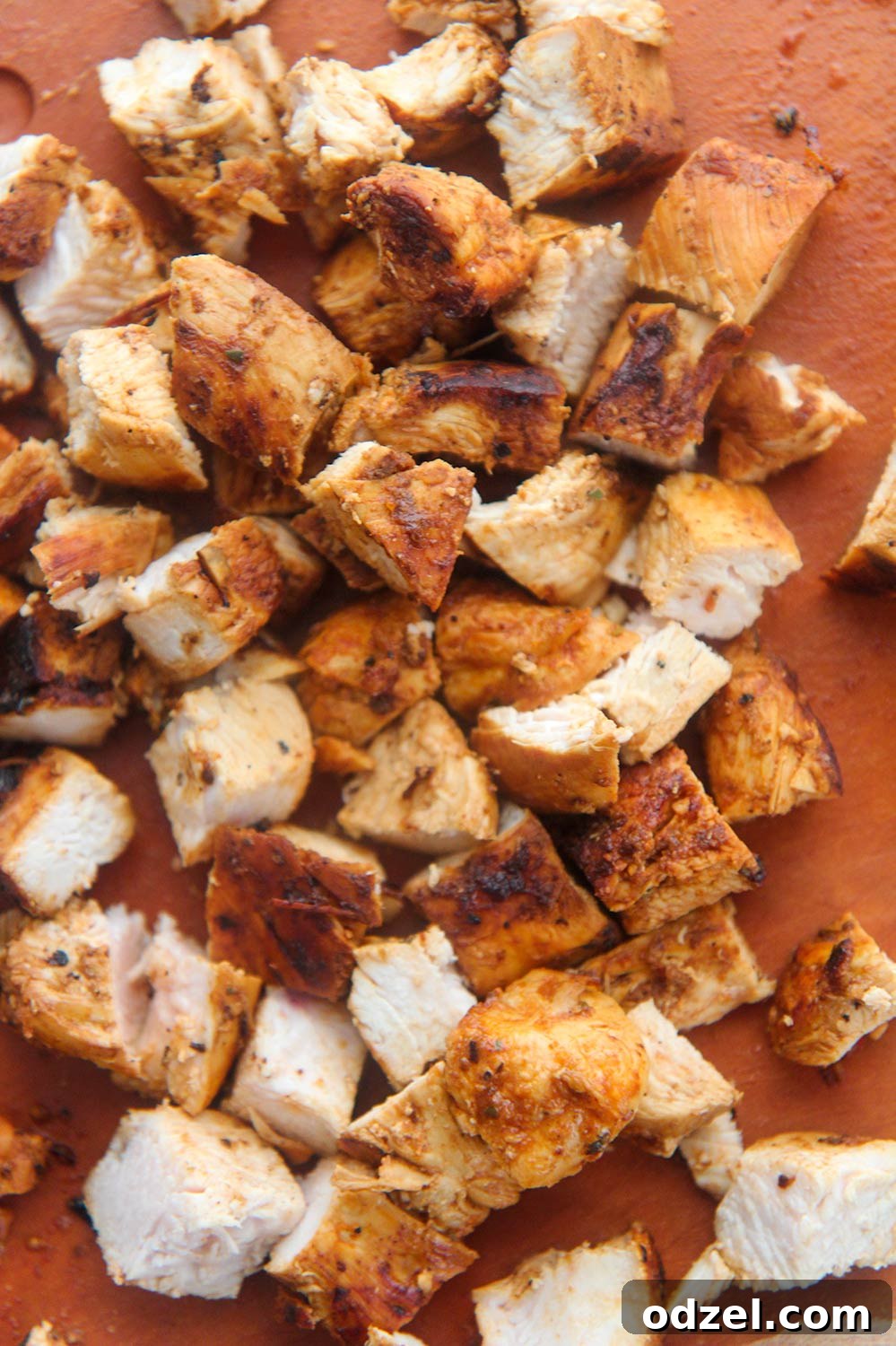 Close-up of perfectly diced chipotle chicken resting on a wooden cutting board, ready for serving.