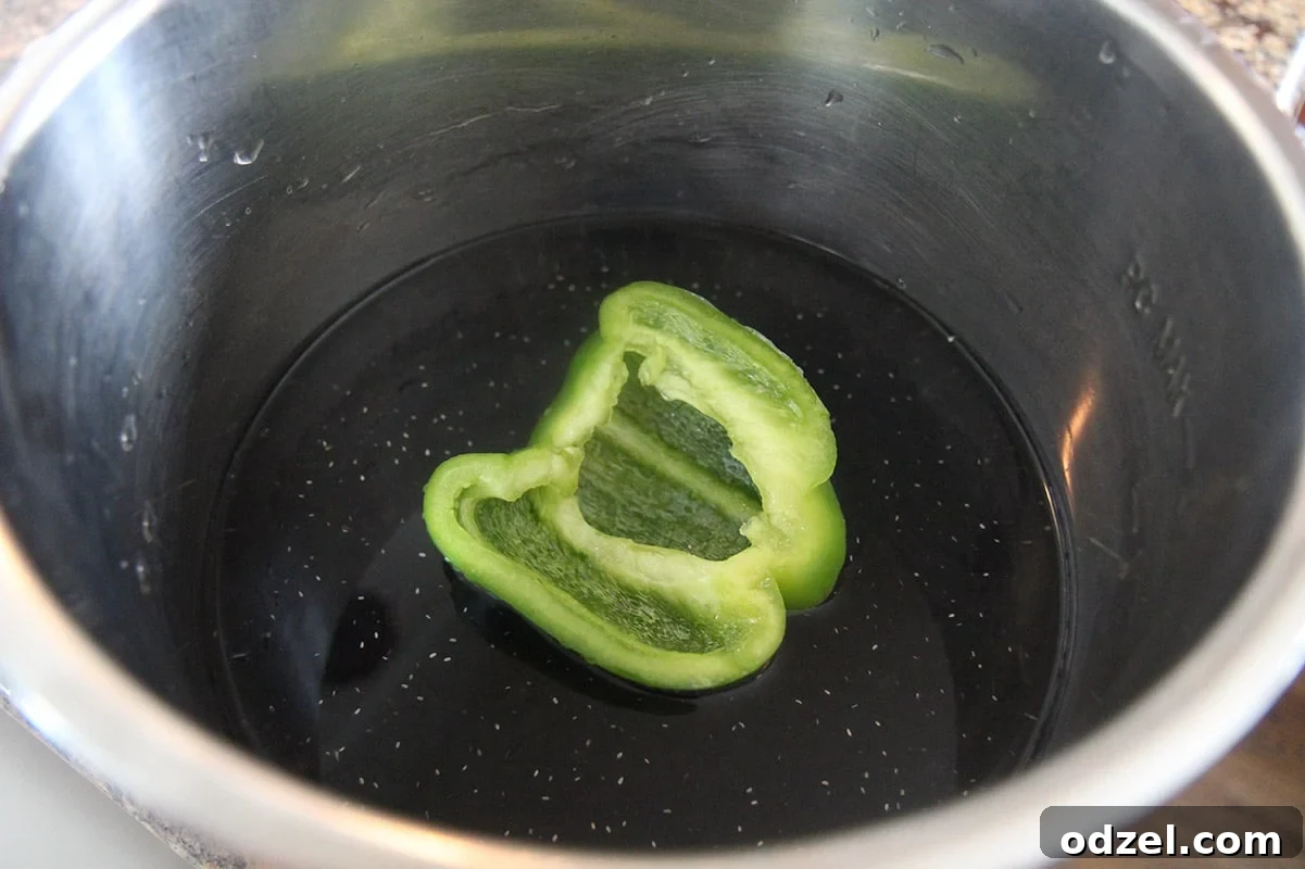 Dried black beans, perfectly measured water, and a piece of green bell pepper inside an Instant Pot, ready to be pressure cooked for Cuban Congri.