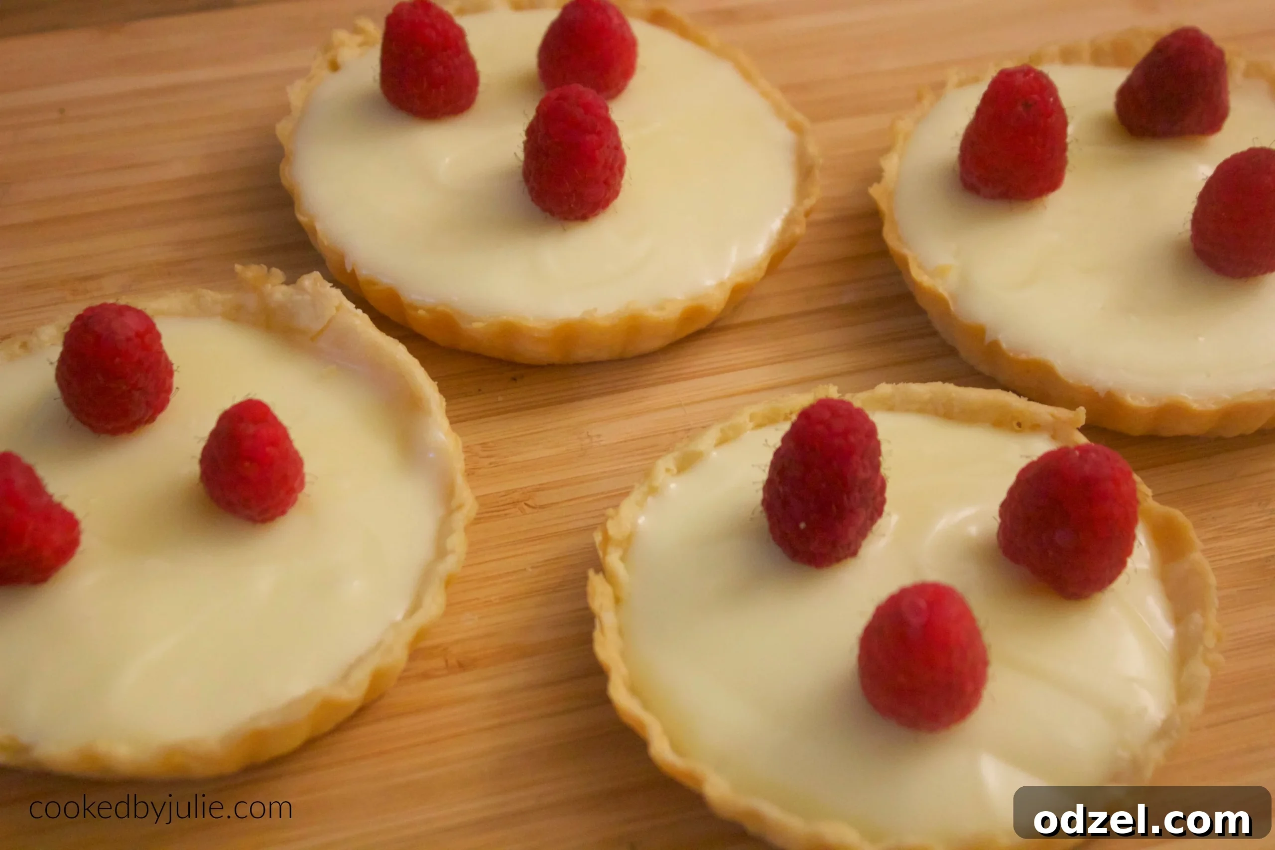 Decadent White Chocolate Tartlets 3 A close-up shot of a white chocolate tart with a slice removed, revealing the creamy texture, garnished with fresh raspberries.