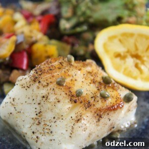 Chilean sea bass with vegetables, salad, and lemon.