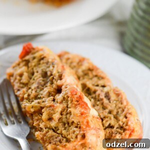 Two slices of Meatloaf Parmesan on a white plate with a fork on the side, ready to be enjoyed.