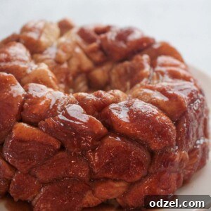 A freshly baked, golden brown caramel monkey bread on a white plate, showcasing its sticky, pull-apart texture.