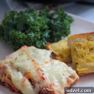 A slice of lasagna with garlic bread and kale salad on the side.