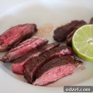 Air fryer carne asada on a white plate with lime on the side, ready to be served.