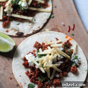 Two vibrant chorizo tacos, generously filled and topped, resting on a rustic wooden board.