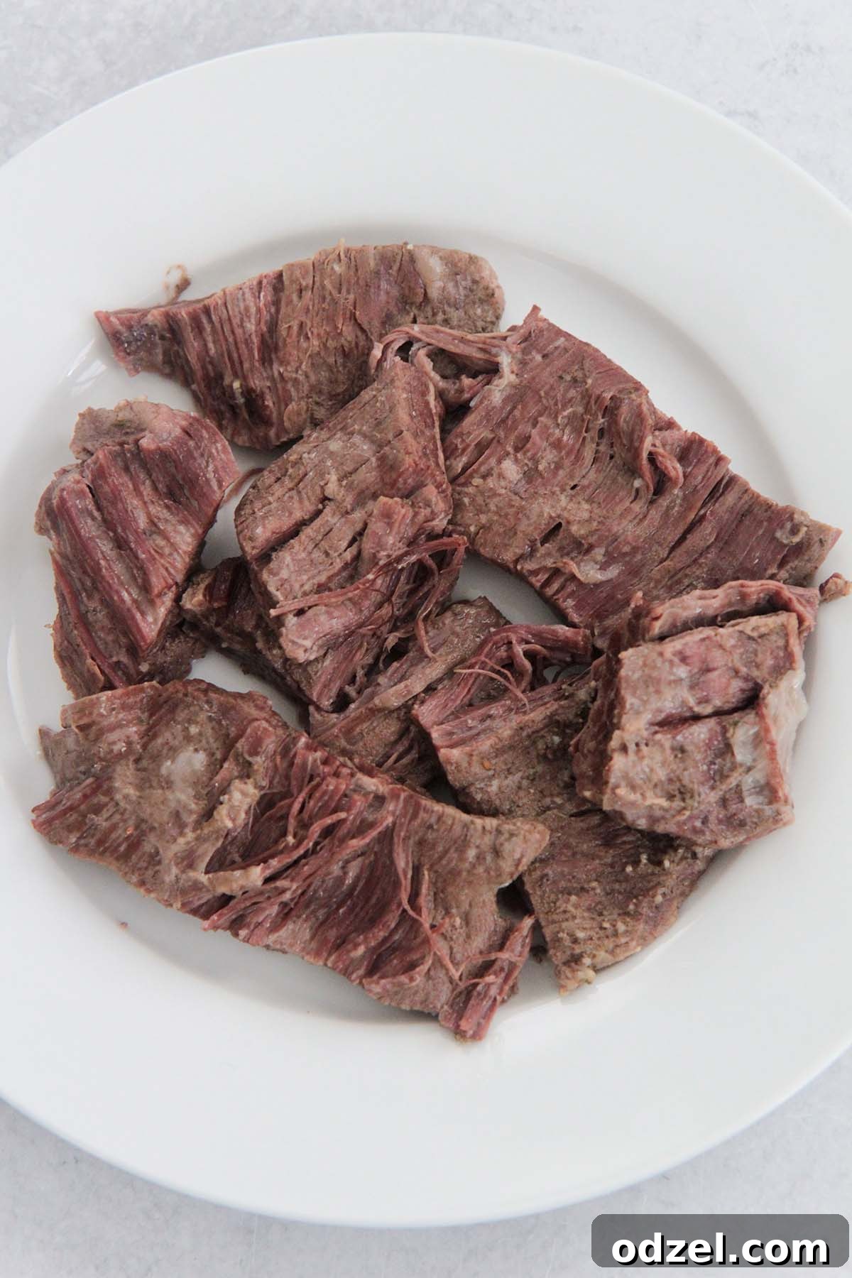 Golden Crispy Shredded Beef 4 Shredded flank steak resting on a white plate, prepared for frying.