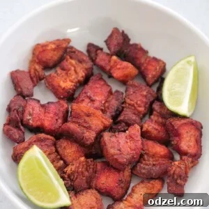 air fryer pork belly in a white plate with two lime wedges.