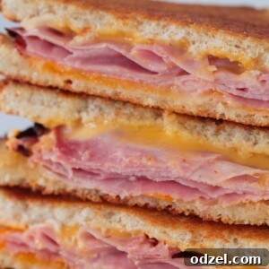 Three air fryer grilled ham and cheese sandwiches stacked neatly on a plate, ready to be enjoyed.