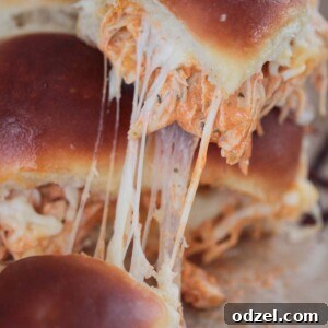 Zesty Buffalo Chicken Minis 2 Close-up of baked buffalo chicken sliders with melted cheese and a golden crust.