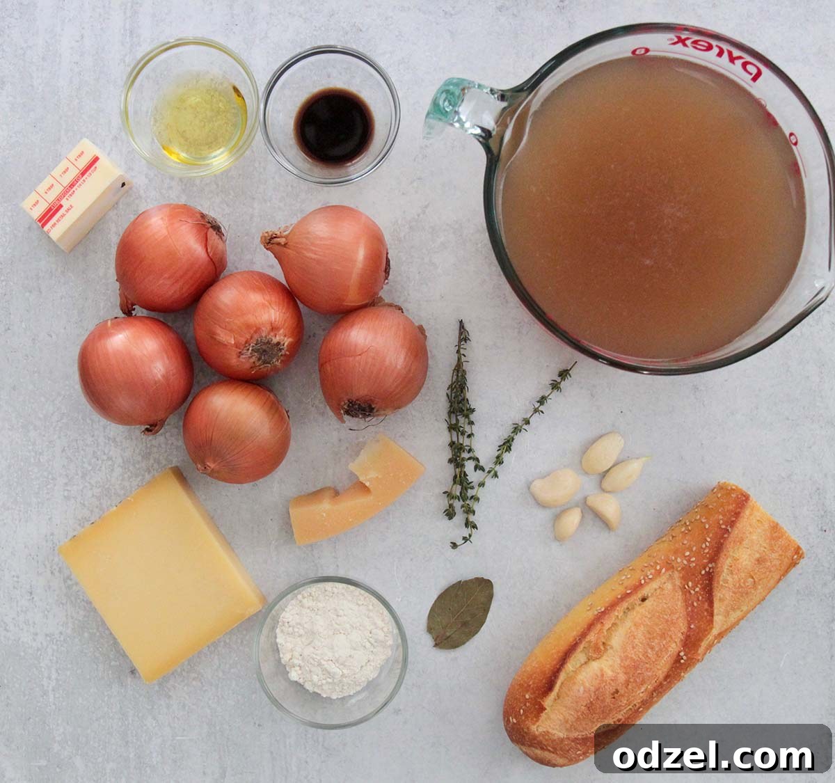 Savory Caramelized Onion Gratin 3 A collection of fresh ingredients laid out on a wooden board, including yellow onions, garlic, fresh thyme, a bottle of red wine, and blocks of cheese, ready for making French onion soup.