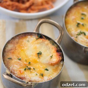 French onions soup with melted cheese and fresh thyme on top.