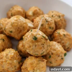 Baked chicken meatballs on a white plate, garnished with fresh herbs.
