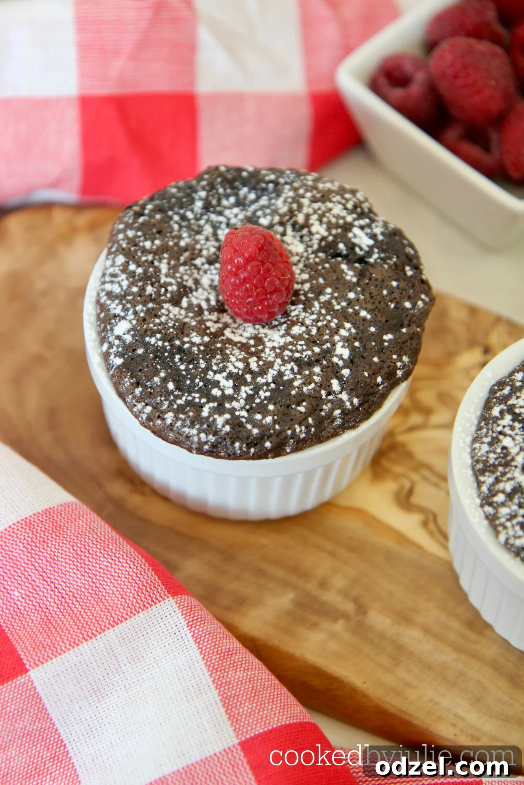 Two mini Nutella cakes, dusted with powdered sugar and garnished with fresh raspberries, presented elegantly for a romantic dessert.
