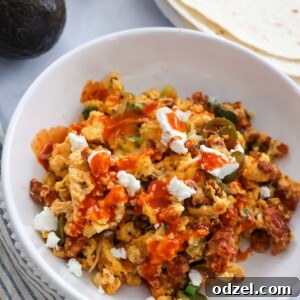 chorizo scrambled eggs with cheese and hot sauce on top.