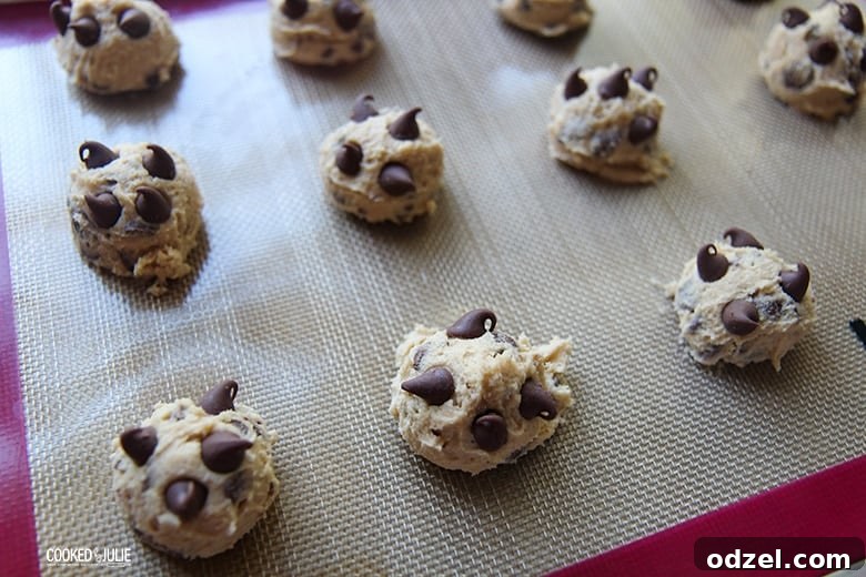 Ultimate Chocolate Chip Indulgence 6 Neatly arranged balls of chocolate chip cookie dough evenly spaced on a baking sheet lined with parchment paper, awaiting their transformation in the oven.