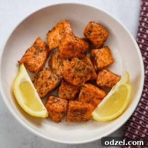Air fryer salmon bites with lemon wedges.
