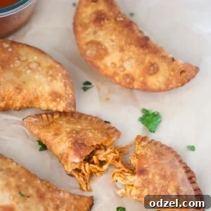 Golden Crispy Chicken Empanadas 2 four chicken empanadas with hot sauce on the side.