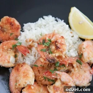 Hawaiian garlic shrimp, white rice, and lemon on a black plate