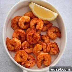 air fryer honey chipotle shrimp in a a white dish with a lemon wedge on the side.