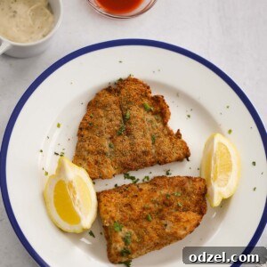 air fryer grouper fillets with lemon wedges, tartar sauce, and hot sauce.
