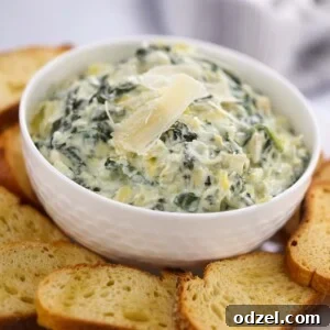 Crockpot spinach artichoke dip in a white bowl with baguette slices.