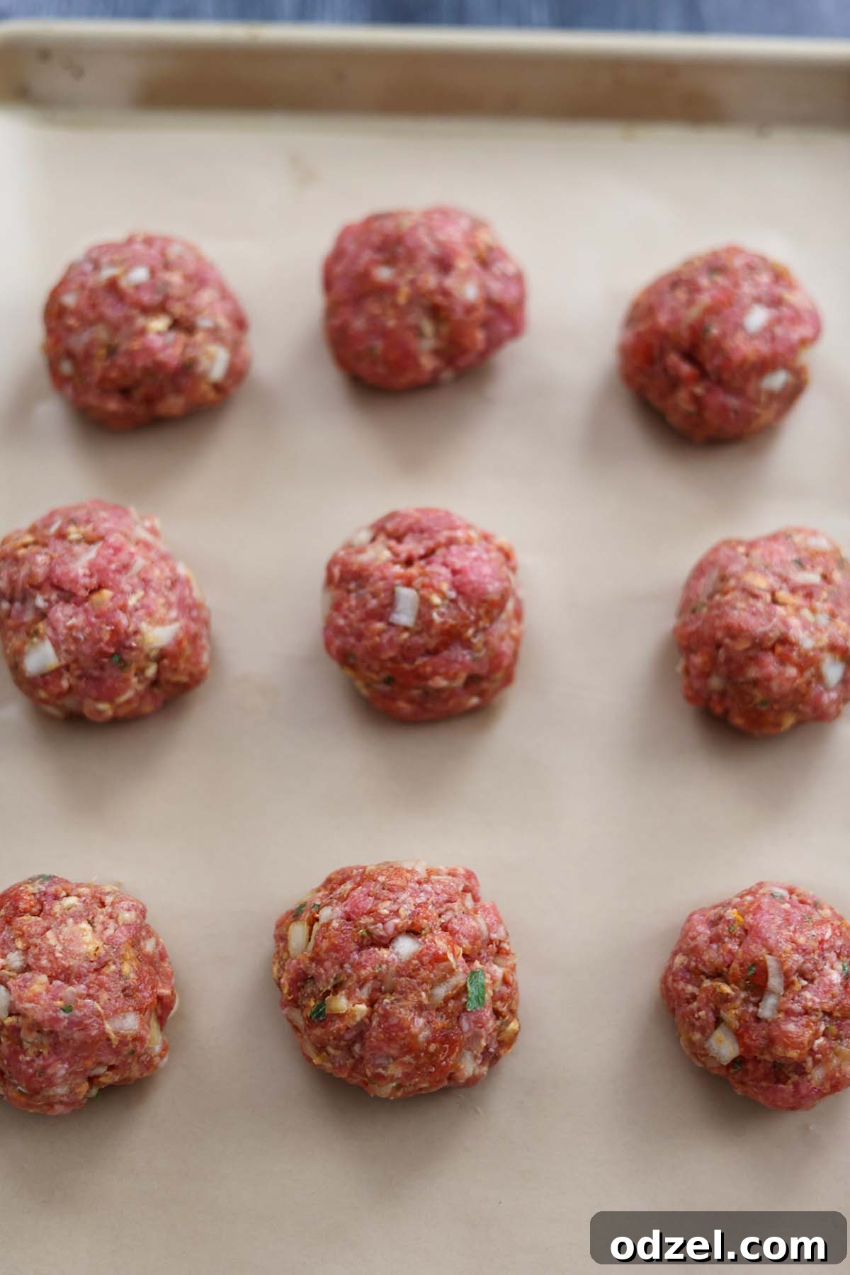 Authentic Cuban Meatballs 3 Rolled raw meatballs neatly arranged on a baking sheet, ready for cooking.