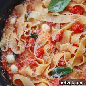 cherry tomato pasta with basil and cheese on top.
