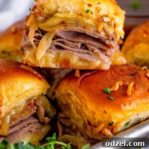 French dip sliders shown up close, highlighting the roast beef and cheese filling.
