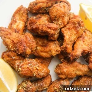 Crispy honey lemon pepper wings on a white plate, garnished with lemon wedges.