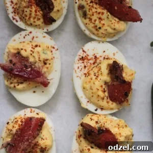 Six candied bacon jalapeno deviled eggs arranged on a serving plate.