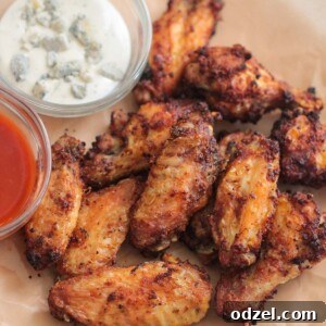 Air fryer chicken wings served on a plate with buffalo sauce and blue cheese dressing on the side.