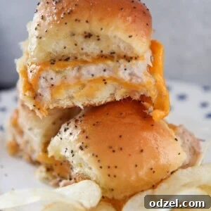 Three hot tuna melt sliders served with a side of potato chips on a plate.