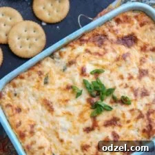 Hot crab dip garnished with green onions and served with Ritz crackers.