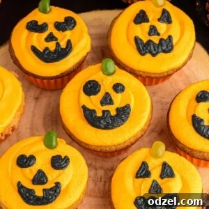 Seven Jack-O'-Lantern cupcakes on a wooden board.