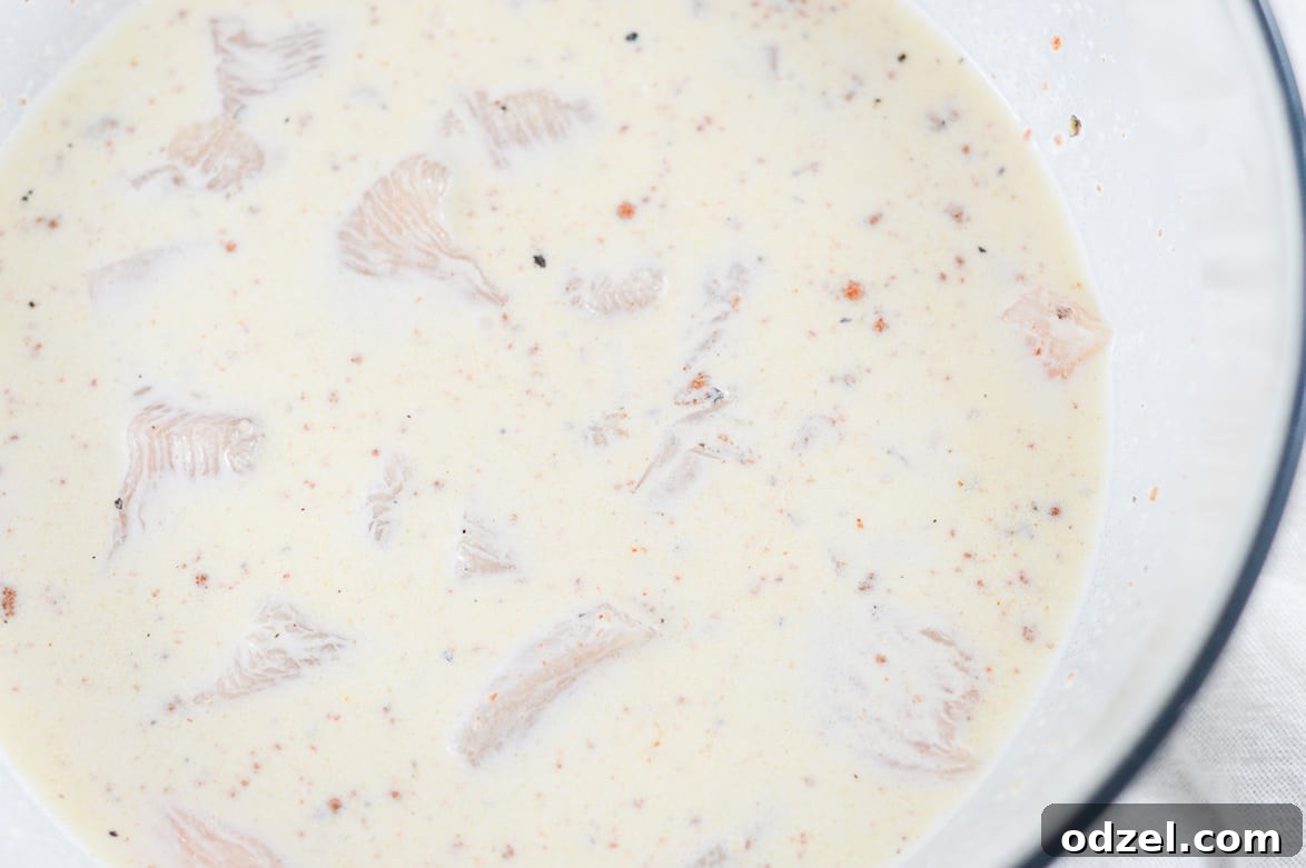 Sweet and Smoky Boneless Chicken Bites 3 chicken coated in buttermilk in a large glass bowl