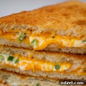 Three golden-brown jalapeno popper grilled cheese sandwiches up close.
