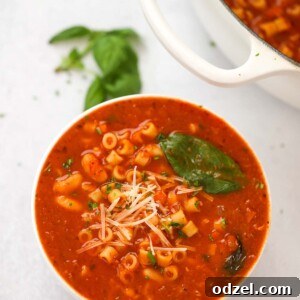 A bowl of Pasta Fagioli soup with a pot on the side, ready to be served.