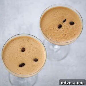The Espresso Elixir 2 Two espresso martinis with foamy tops and coffee beans.