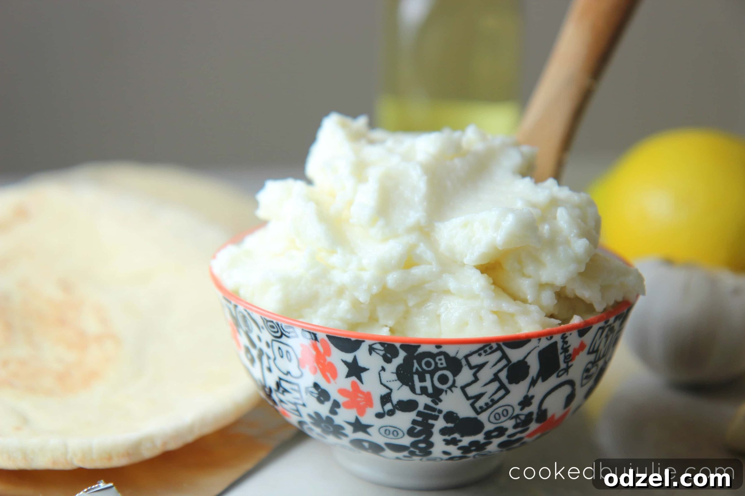 Creamy Lebanese Garlic Toum 4 Traditional Lebanese garlic sauce is low carb and perfect for dipping some pita bread or veggies, shown in a bowl with pita and olives.
