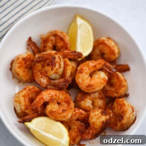 Pan seared shrimp in a bowl with lemon wedges on the side.