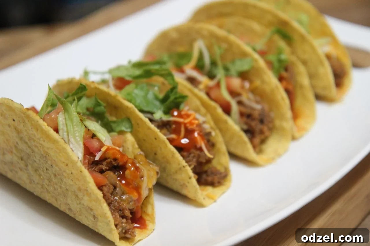 Delicious crispy beef hard shell tacos filled with seasoned ground beef, cheese, lettuce, and tomatoes, ready for a fun taco night.