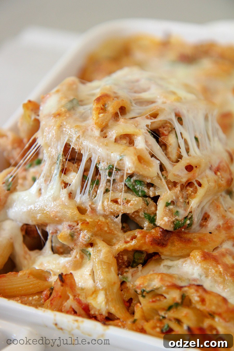 A spoonful of baked ziti with spinach, showing melted cheese and pasta.
