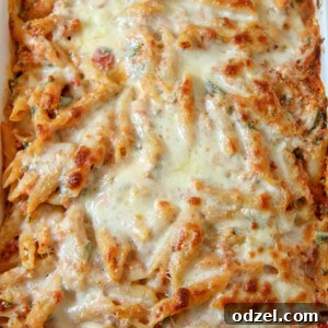 Baked Ziti with Spinach and melted mozzarella cheese on top in a white casserole dish.