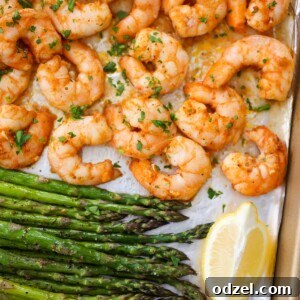 Baked shrimp and asparagus with lemon wedges, beautifully presented as a quick and healthy meal.