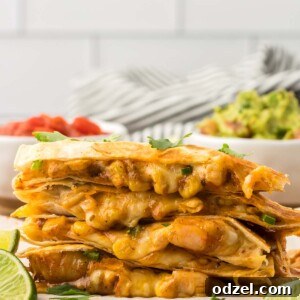 Four shrimp quesadillas stacked with limes and guacamole on the side.