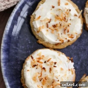 two coconut cookies with cream cheese frosting on a blue plate.