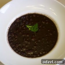 A vibrant bowl of homemade Cuban black beans, rich and savory, ready to be served with traditional accompaniments.
