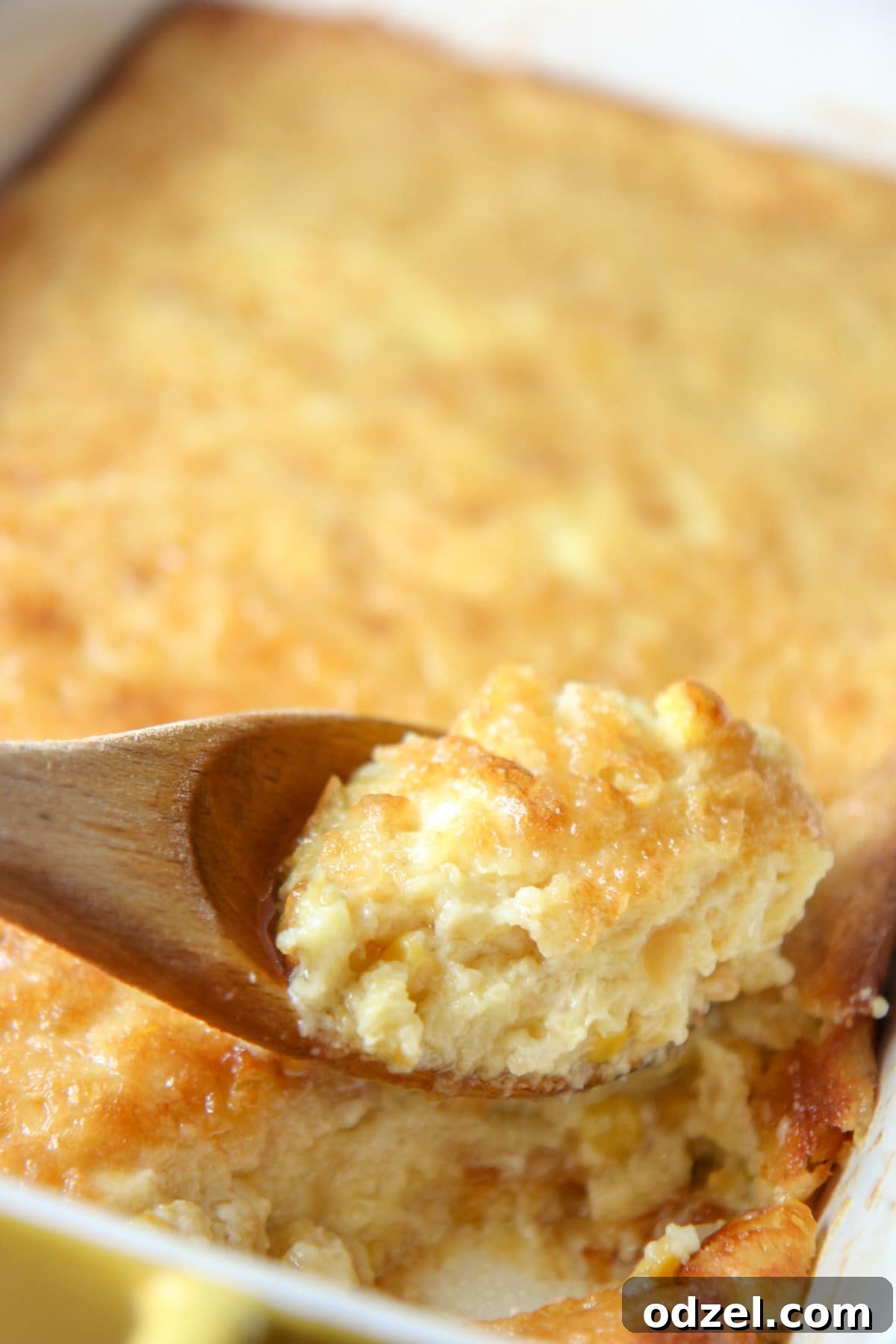 A spoonful of creamy corn pudding, showing its moist and jiggly texture, perfect for holiday meals.