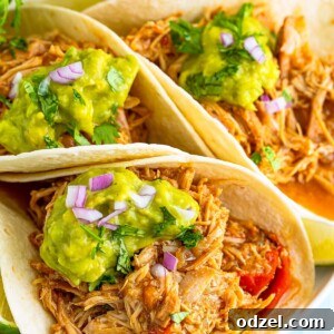 Three shredded chicken tacos with guacamole on top.